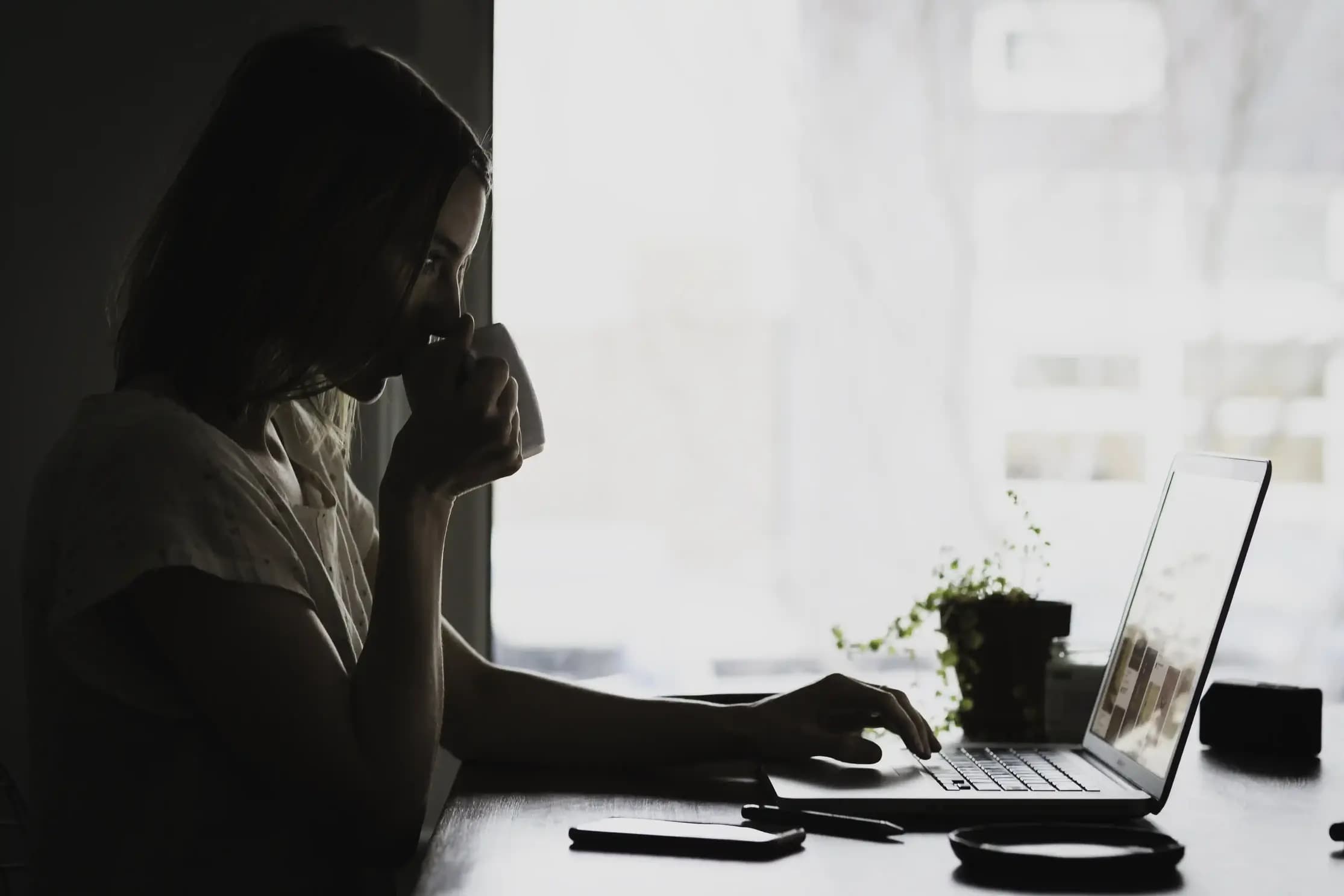 Vrouw achter laptop drinkt een kop thee en kijkt wat er mis is met haar website content