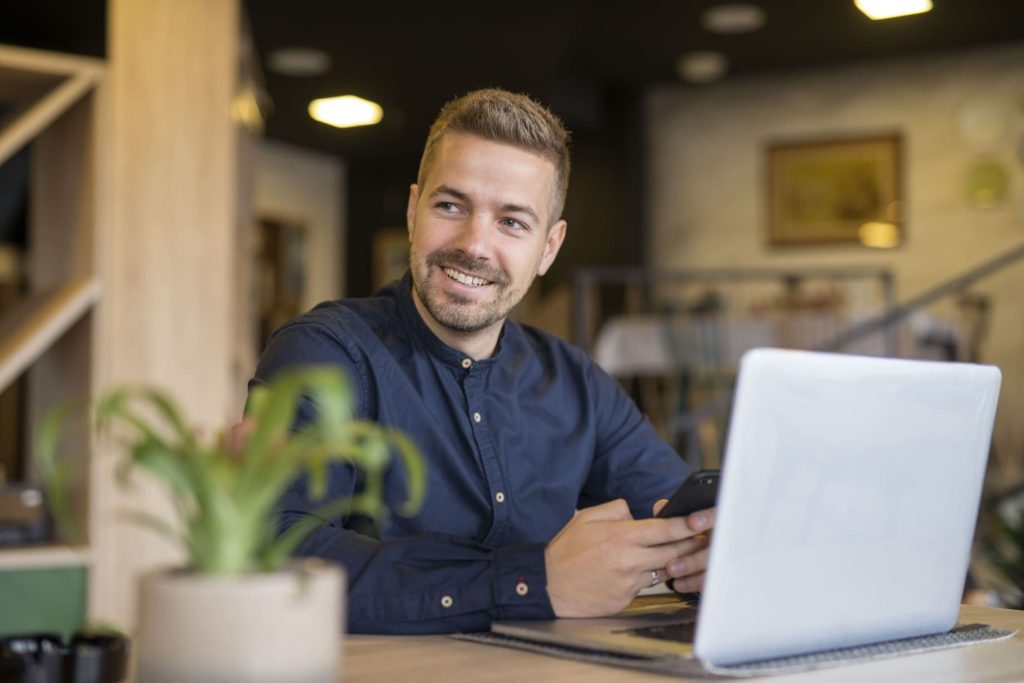 young-businessman-sitting-cozy-cafe-bar-using-laptop-computer-looking-aside