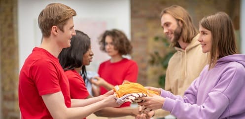 Groepje jongens en meisjes geven shirts aan elkaar over