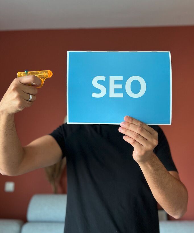 man houdt waterpistool tegen tekst SEO aan en geeft daarmee het idee dat SEO dood is